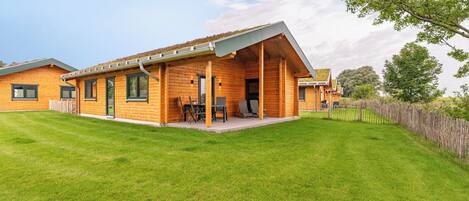 A two-story wooden house with a covered patio and a well-maintained lawn.