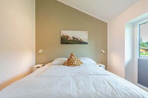 A hotel room with a bed, a painting of sheep on the wall, and a window with a view of a building. - "Huus Schoop" Vacation Home in Kating for up to 4 people (Kating)