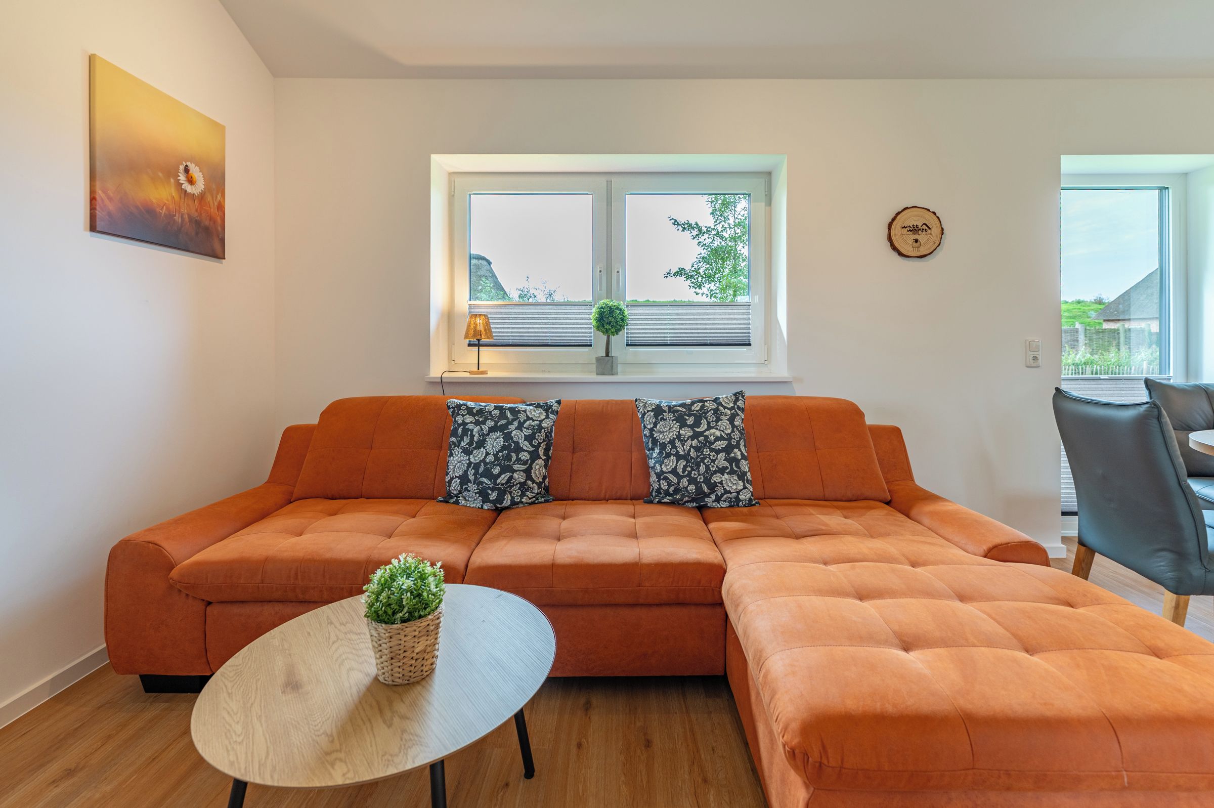 A modern living room with a sectional sofa, a round table, and a window with blinds.