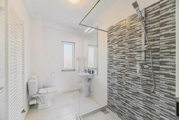 Un baño moderno con inodoro, lavamanos y ducha.