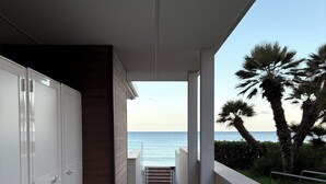 En gang der fører til en balkon med udsigt over havet og palmer.