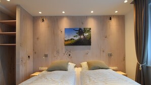 Una cama doble con ropa de cama estampada, una obra de arte colgada en la pared y un panel de pared de madera.