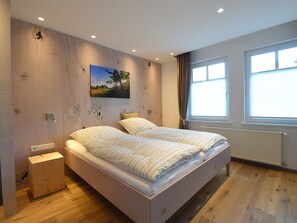 Ein Schlafzimmer mit Bett, Nachttisch, Gemälde und Fenster.