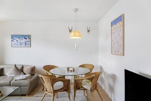 A living room with a glass table, wicker chairs, a sofa, a hanging light, and wall-mounted art. - Apartment 'Haus Excelsior Top 32' with Mountain View, Balcony and Wi-Fi (Seefeld in Tirol)