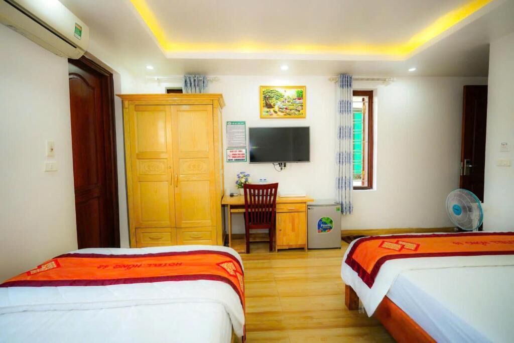Habitación de hotel con dos camas, un escritorio, una silla, un televisor y un refrigerador pequeño.