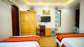 Habitación de hotel con dos camas, un escritorio, una silla, un televisor y un refrigerador pequeño.