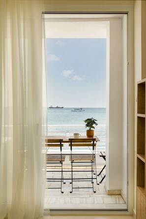 Een balkon met uitzicht op zee, een bloempot en een tafel met stoelen.