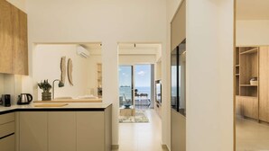 Una cucina moderna con isola centrale, zona pranzo con vista mare e un ampio soggiorno con una grande finestra.