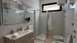 Moderni kylpyhuone, jossa on lasinen suihkuseinä, kaksi allasta sisältävä pesuallas ja wc.