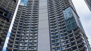 Un immeuble de grande hauteur doté d’une architecture moderne, caractérisé par une bande verticale centrale et de nombreux balcons.