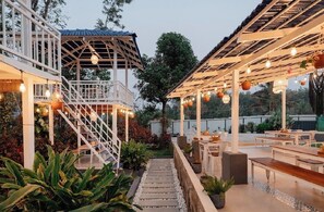 An outdoor patio area with a covered seating area, a staircase, and potted plants. - AETHERIA ESTATE RETREAT (Chikkamagaluru)