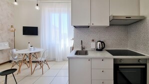 Cozinha compacta com pia, fogão e pequena área de refeições com mesa e cadeiras.