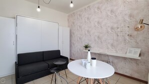 A modern living room with a black sofa, a round white table, and a patterned wallpaper. - Italianway Easy - Gallura 9 (Milan)