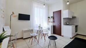 A compact living space with a dining area, kitchenette, and a TV mounted on the wall. - Italianway Easy - Gallura 9 (Milan)