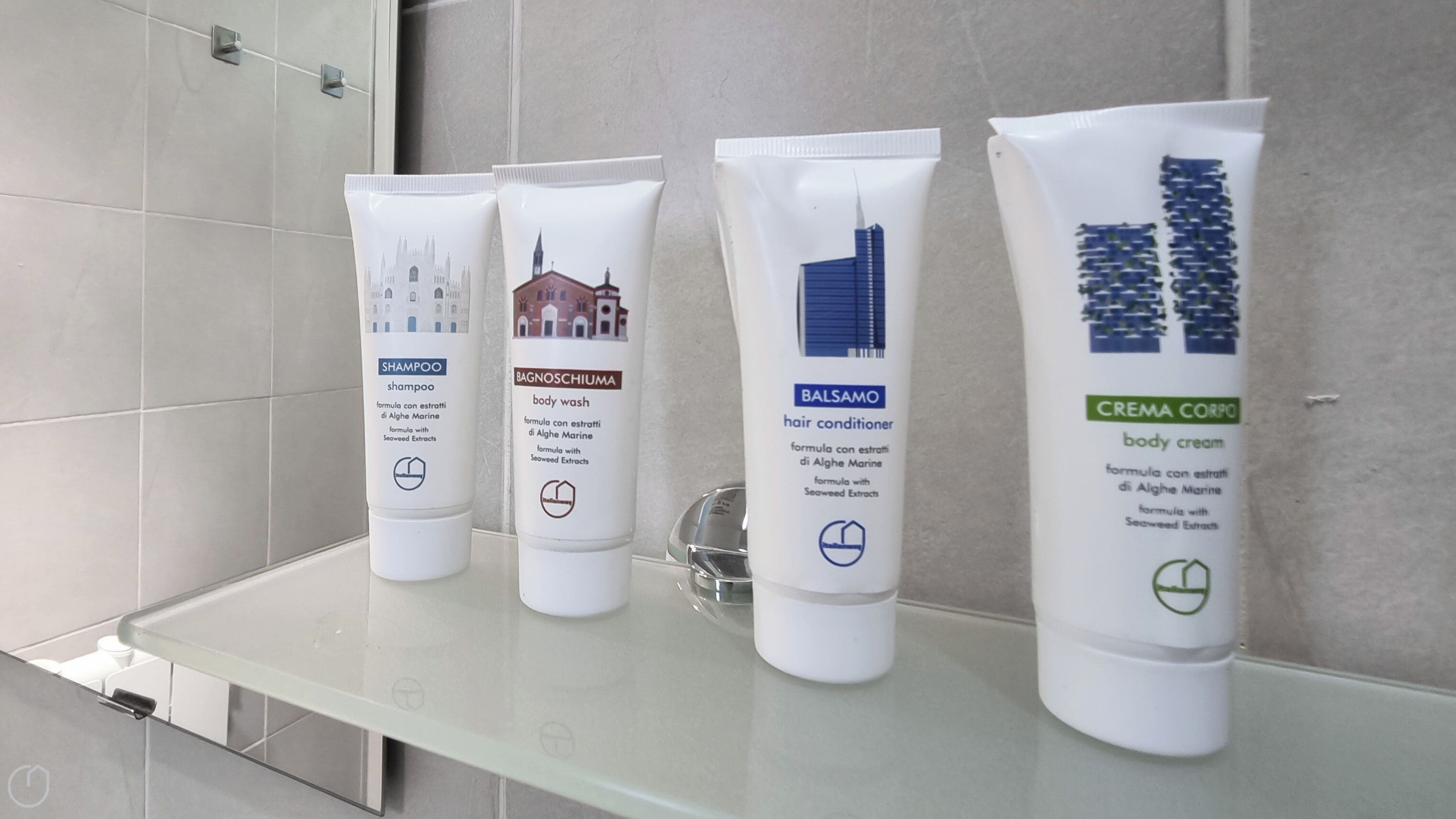 Four toiletry bottles on a bathroom shelf.