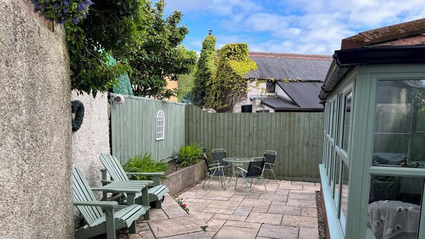 Un espace patio avec une table et des chaises, une clôture en bois et une fenêtre.