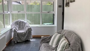 Une pièce confortable avec une grande fenêtre, un fauteuil, un canapé et un radiateur.