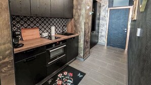 A modern kitchen with dark wood cabinets, a black countertop, and a patterned backsplash.