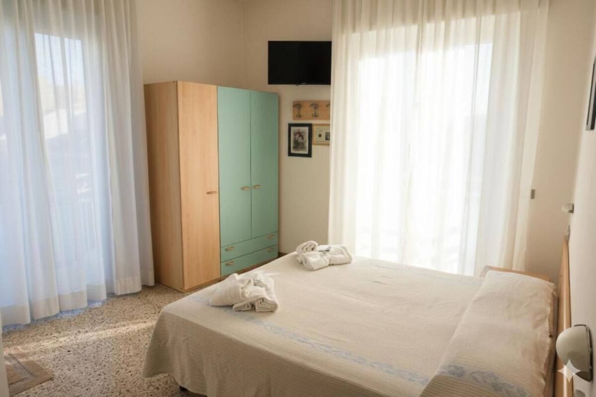 A bedroom with a bed, a wardrobe, and a television on the wall.