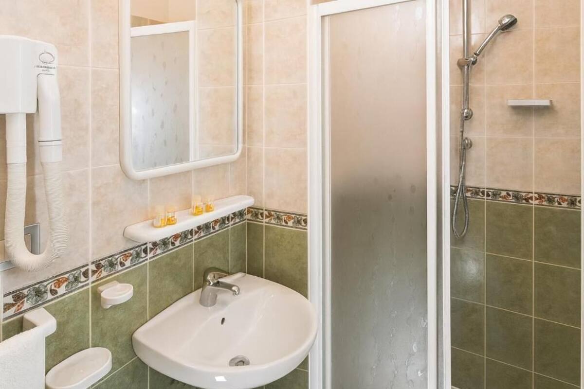 A bathroom with a sink, mirror, and shower.