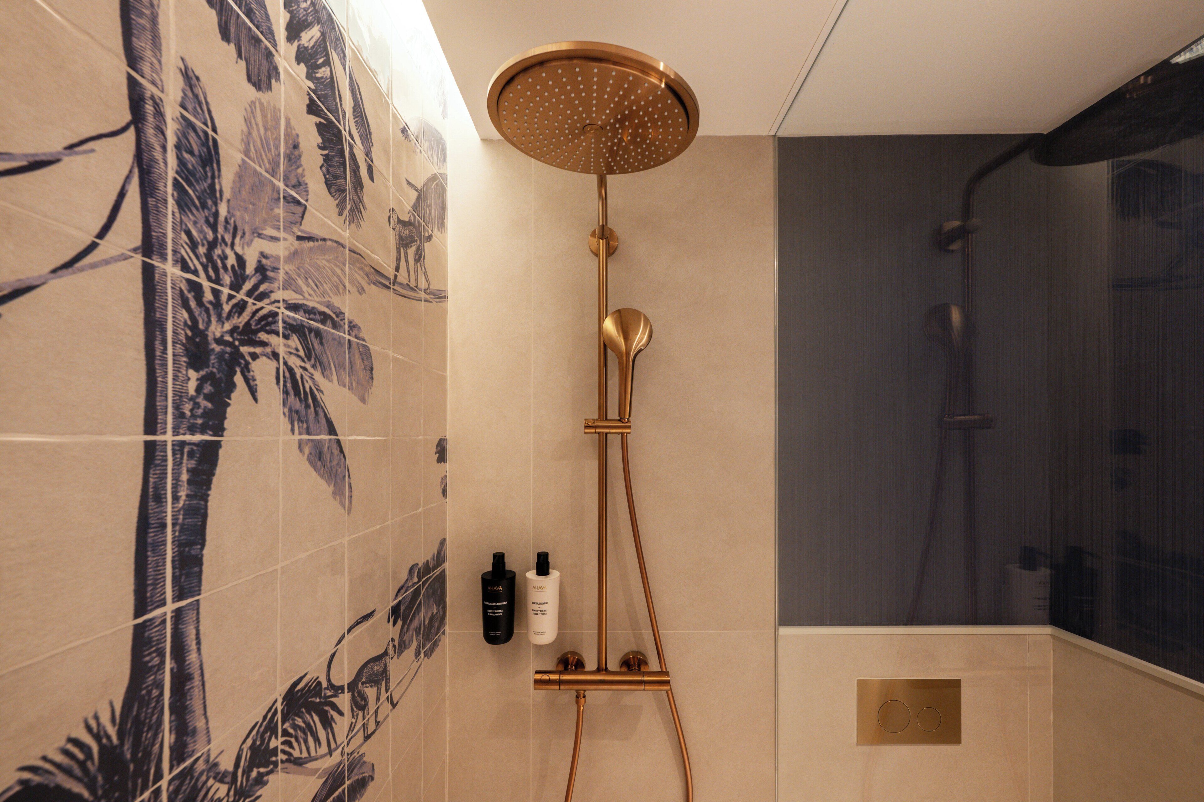 Een badkamer met een douche, betegelde wanden en een decoratief wandpaneel.