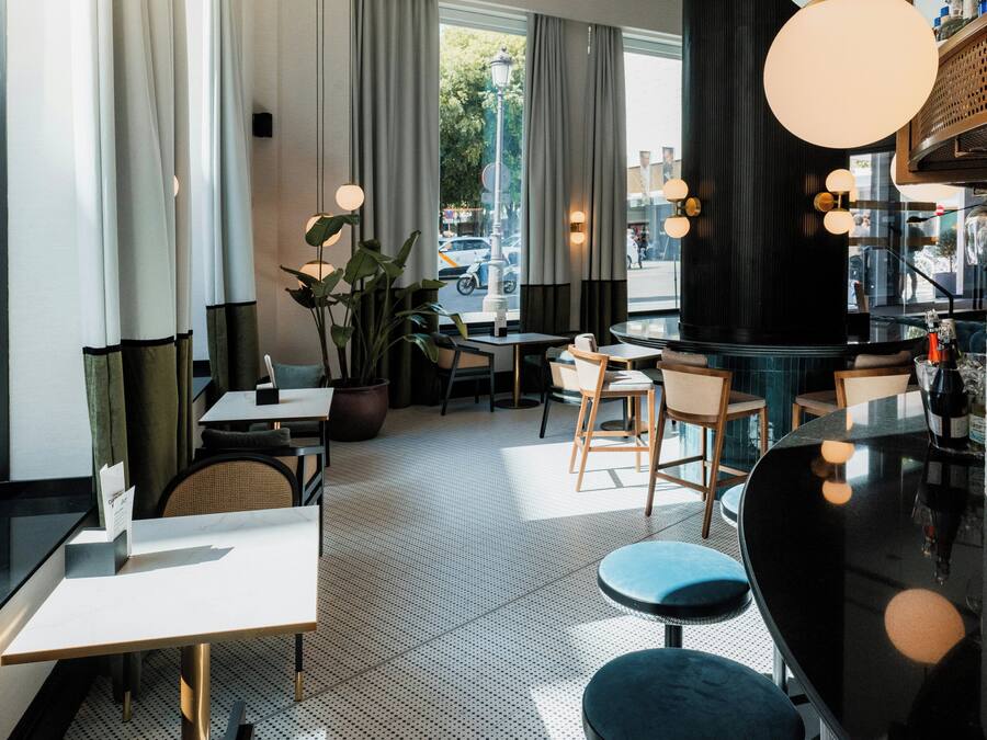 Un interior moderno con zona de bar, asientos y ventanas amplias.