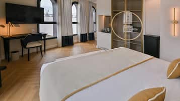 A hotel room with a bed, desk, chair, TV, wardrobe, and a view through the window.