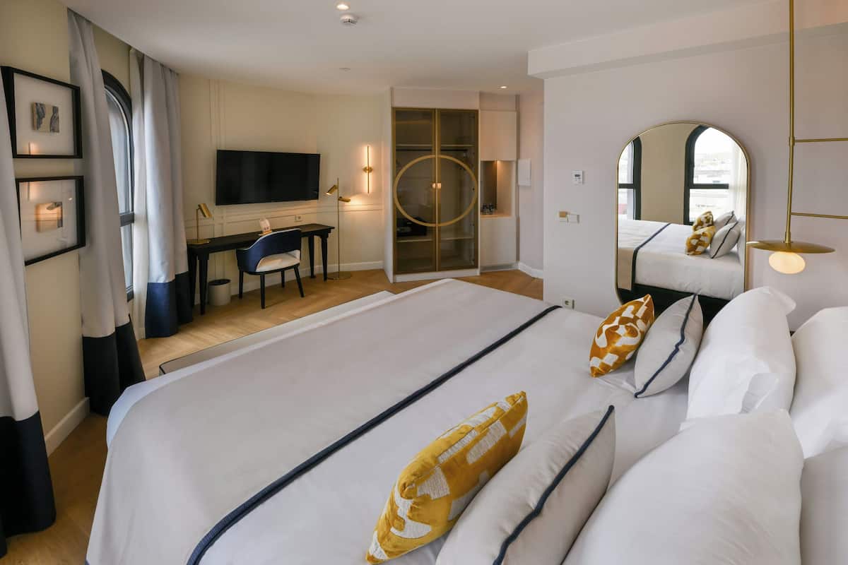 A hotel room with a large bed, a desk, a TV, and a walk-in closet.