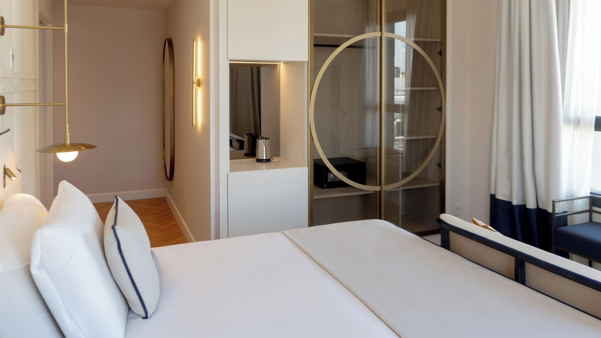 Ein modernes Hotelzimmer mit einem großen Bett, einem begehbaren Kleiderschrank und einer runden Glastür.