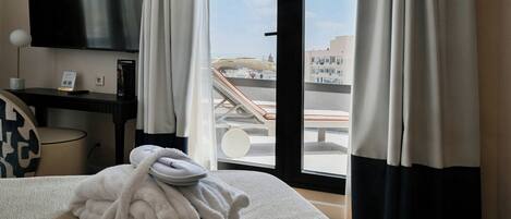 Habitación de hotel con cama, televisión, escritorio y vista a la ciudad desde la ventana.