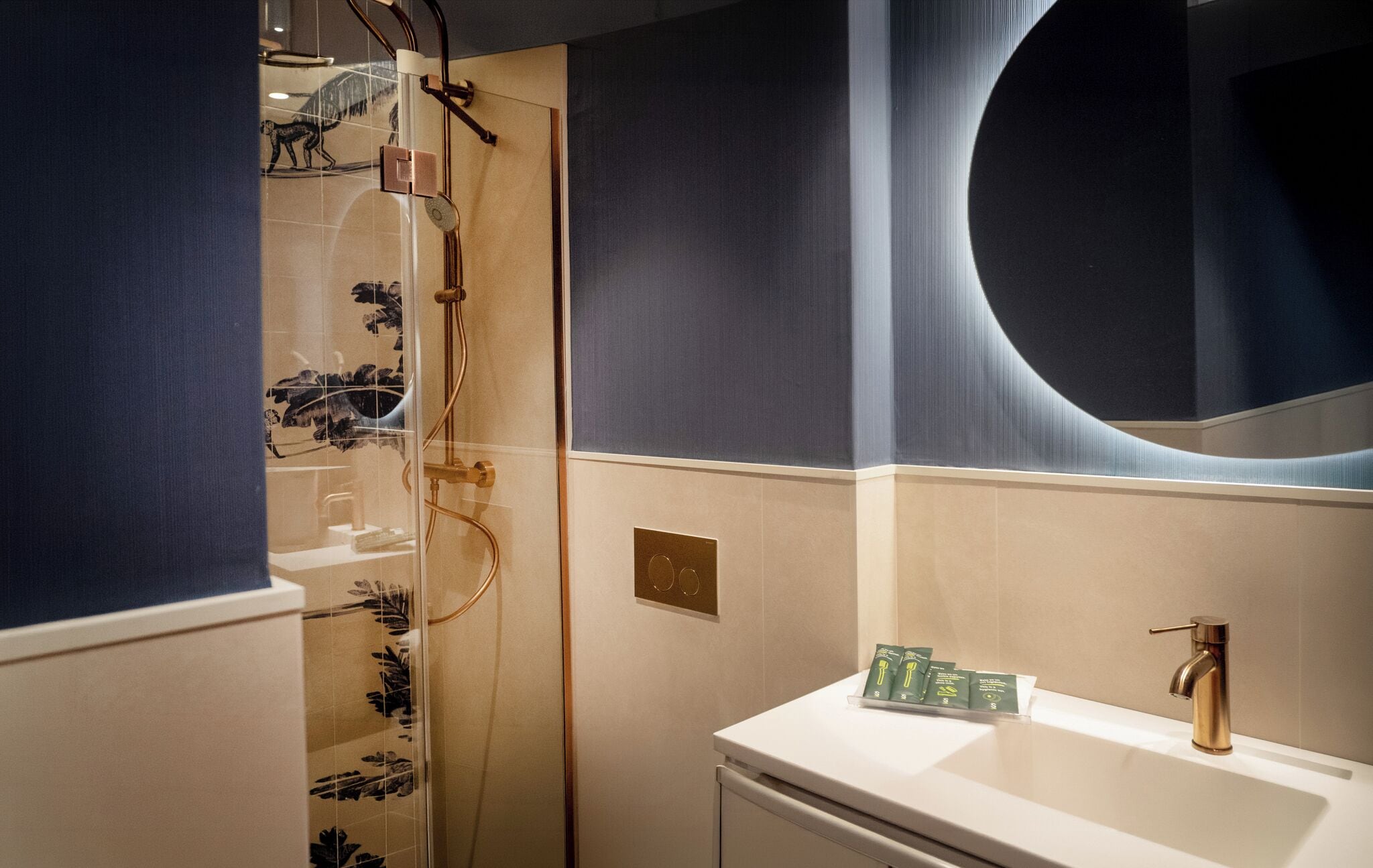 A bathroom with a glass shower enclosure, a sink with a gold faucet, and a large mirror.