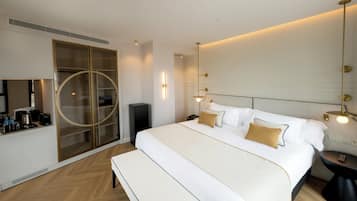 A hotel room with a large bed, a bench, a bedside table, a mirror, a wardrobe, and a television.