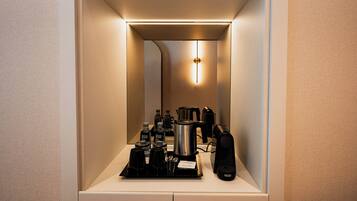 Quarto de hotel compacto com cozinha compacta, incluindo cafeteira, chaleira e outros eletrodomésticos.