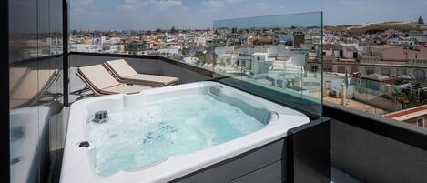 A hot tub on a balcony with a city view.