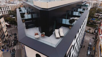 Une terrasse sur le toit, aménagée avec des sièges et offrant une vue sur le paysage urbain.