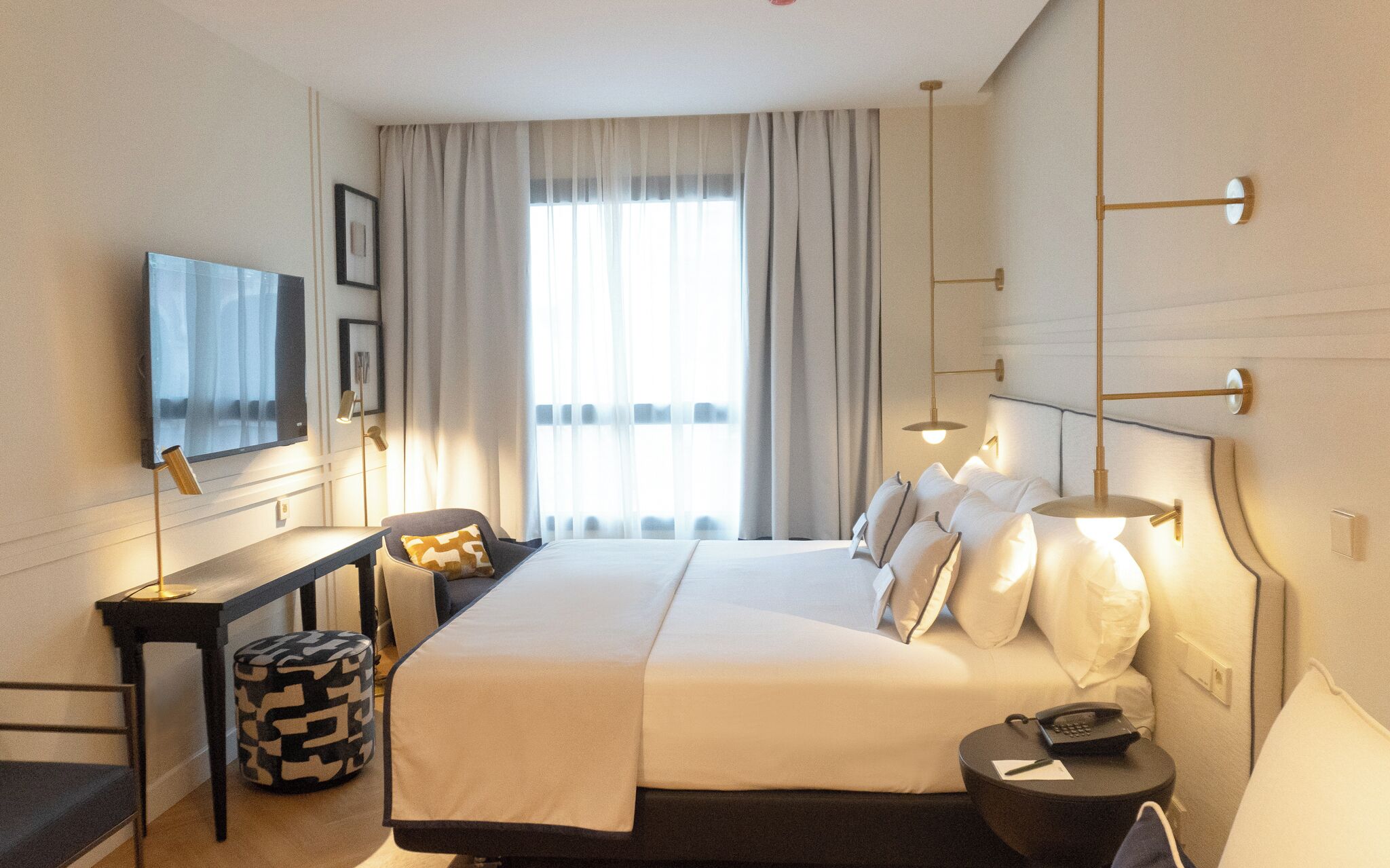 Une chambre d’hôtel moderne dotée d’un grand lit, d’un bureau avec une chaise, d’une télévision et d’une table de chevet avec un téléphone.