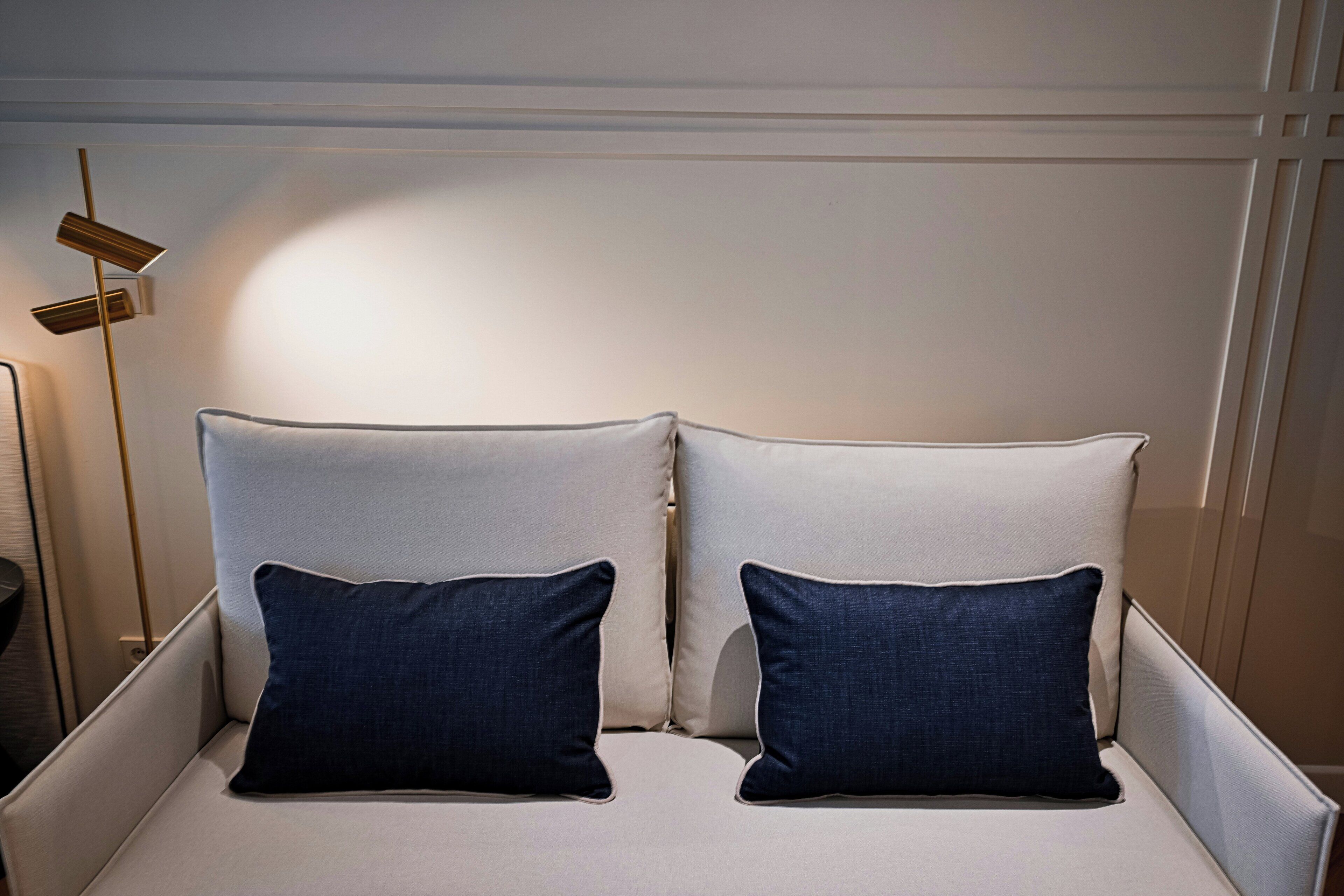 A bed with two pillows, a bedside table, and a floor lamp.