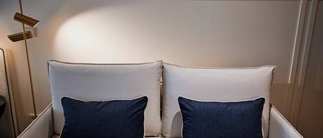 A bed with two pillows, a bedside table, and a floor lamp.