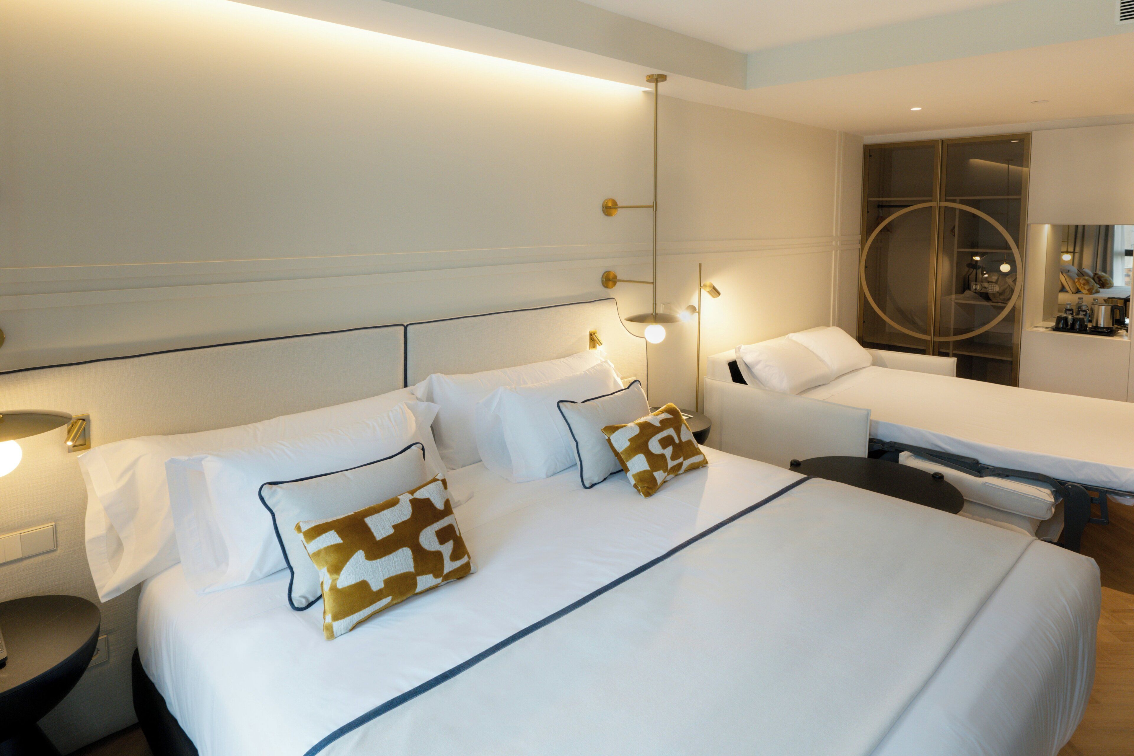 A hotel room with a large bed, bedside tables, a desk, and a mirror.