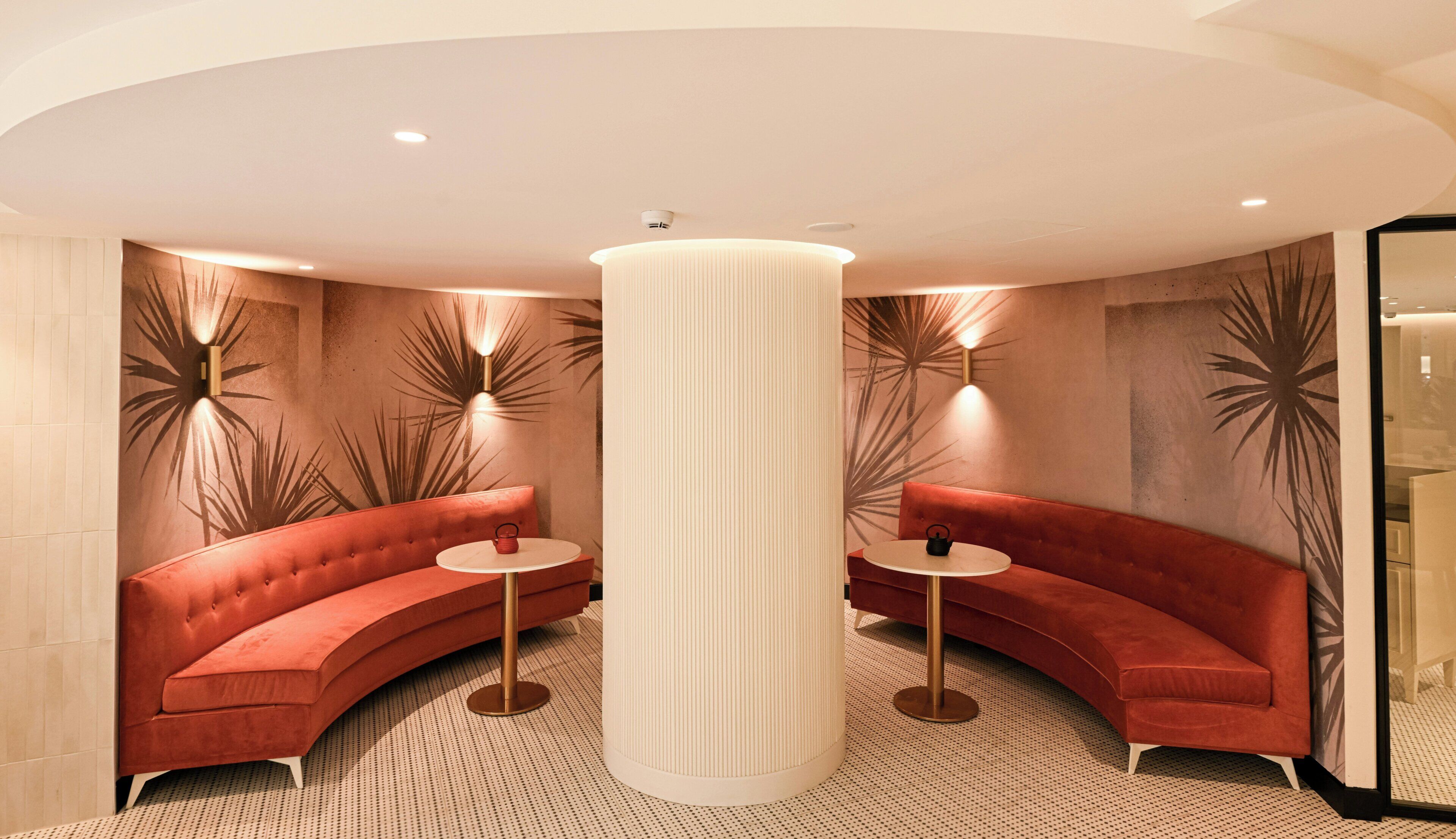 A modern room with a curved red sofa, a round table, and a tall column.