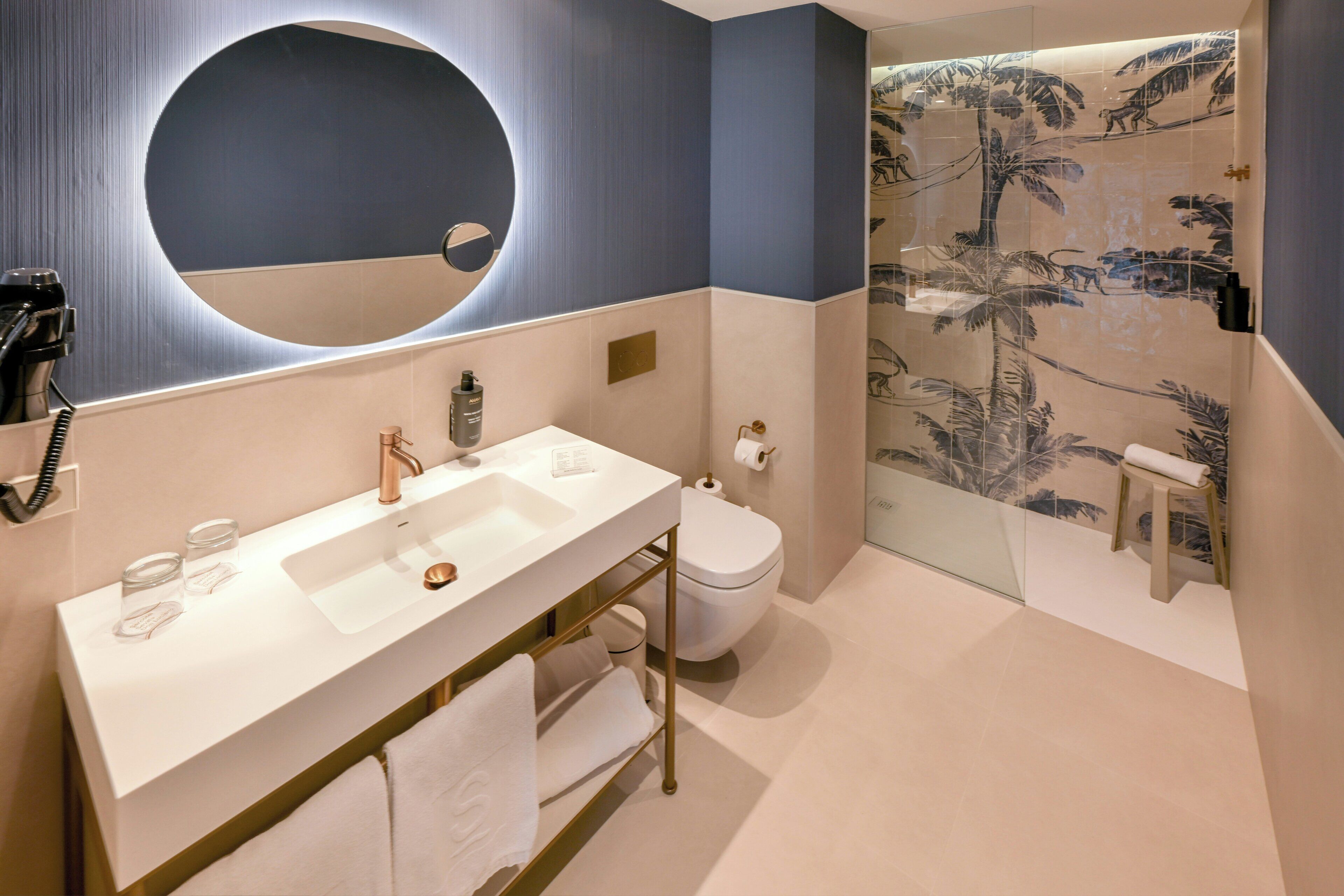 A modern bathroom with a dual sink vanity, a toilet, a glass shower enclosure, and a large mirror.