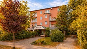 Un hôtel appelé PHONIX, doté d’une façade moderne, d’une entrée abritée et d’un jardin bien entretenu.