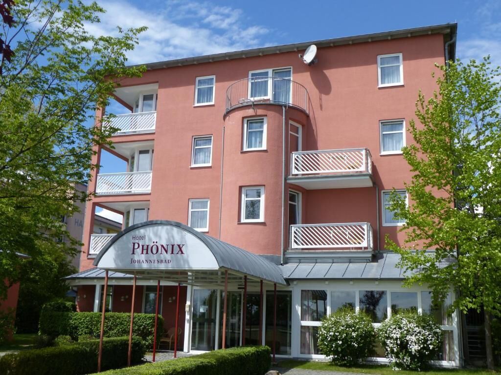 Ein Hotel namens 'Phönix' mit roter Fassade, mehreren Balkonen und einem überdachten Eingang.