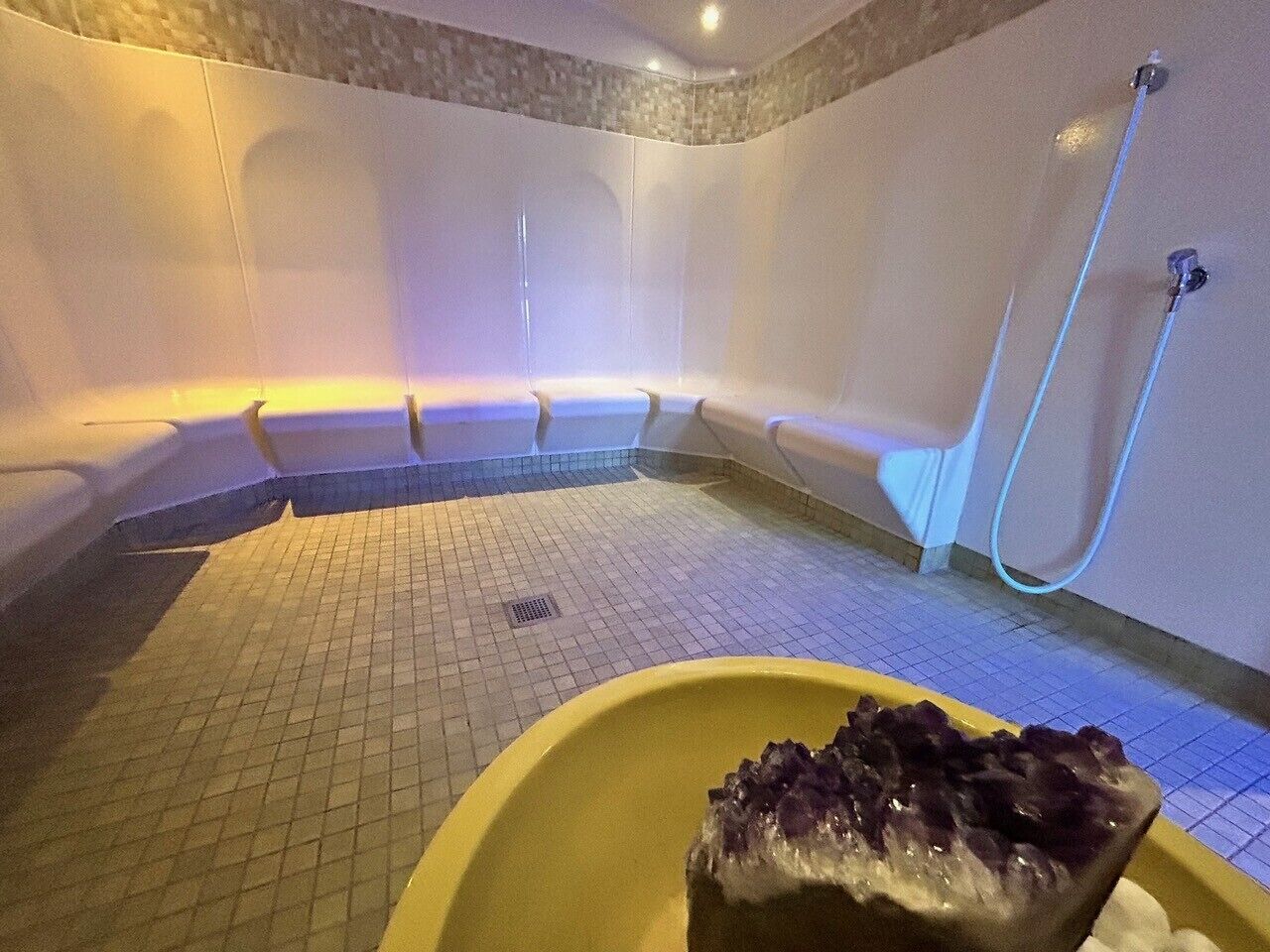 Et spa-rum med jacuzzi, en gul skål med is og et bruseområde.