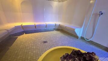 Et spa-rum med jacuzzi, en gul skål med is og et bruseområde.