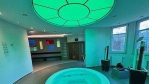 Un espace spa comprenant un jacuzzi circulaire, un luminaire au plafond et des plantes en pot.