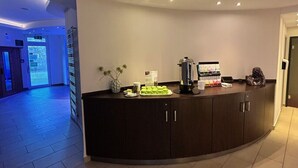 Un espace d’accueil avec un comptoir incurvé, une machine à café et une petite plante.