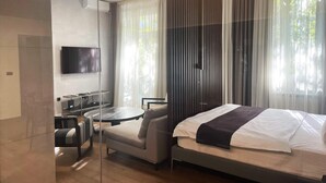 Una camera d'albergo moderna con un letto, una scrivania, una sedia e una televisione.