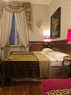 A hotel room with a double bed, a nightstand with a lamp, a painting on the wall, and a window with curtains. - Deluxe room with private bathroom inside (Roma)