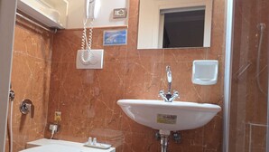 Une salle de bain avec un lavabo blanc, des toilettes et une douche. Il y a un panneau sur le mur et une petite fenêtre au-dessus du lavabo.